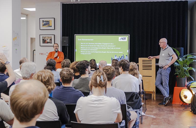 Dieses Bild zeigt Dr. Oliver Parodi, Leiter der Forschungsgruppe „Karlsruher Transformationszentrum für Nachhaltigkeit und Kulturwandel“ (KAT) vor einem bunt gemischten Publikum.