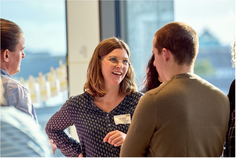 Mehrere Personen im Gespräch bei einer Veranstaltung in hellem, modernem Raum.