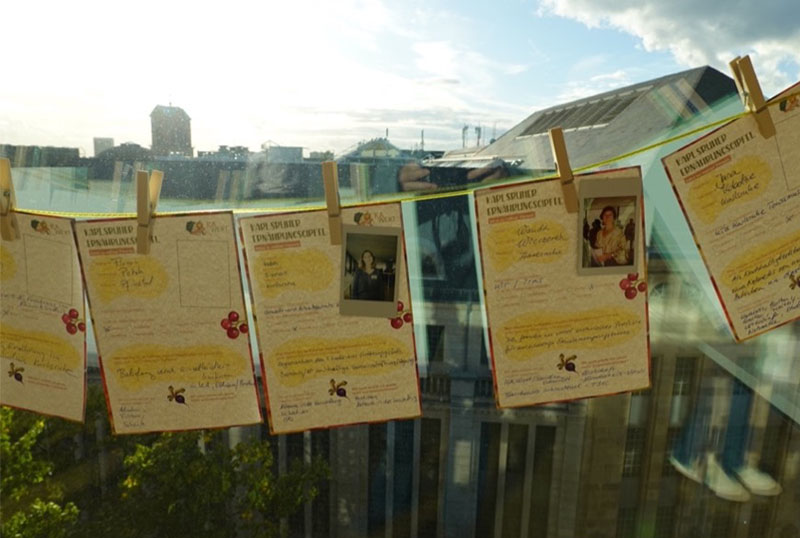 Karten und Steckbriefe hängen an einer Wäscheleine vor Fenster mit Stadtblick.