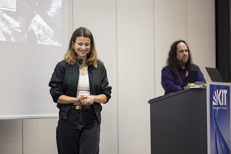 Luisa Neubauer gibt eine Präsentation; eine weitere Person steht vor der Leinwand.