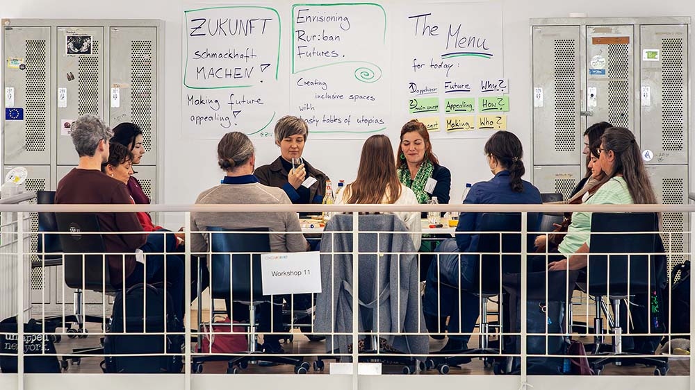 Personen sitzen vor Whiteboard mit Notizen.