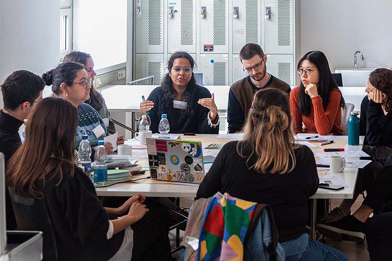 Gruppe Forschender der Reallabor-Konferenz sitzt um einen Tisch und diskutiert.
