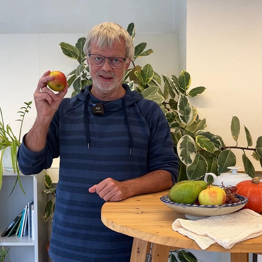 Volker Stelzer steht an einem Stehtisch und hält einen Apfel in der rechten Hand.