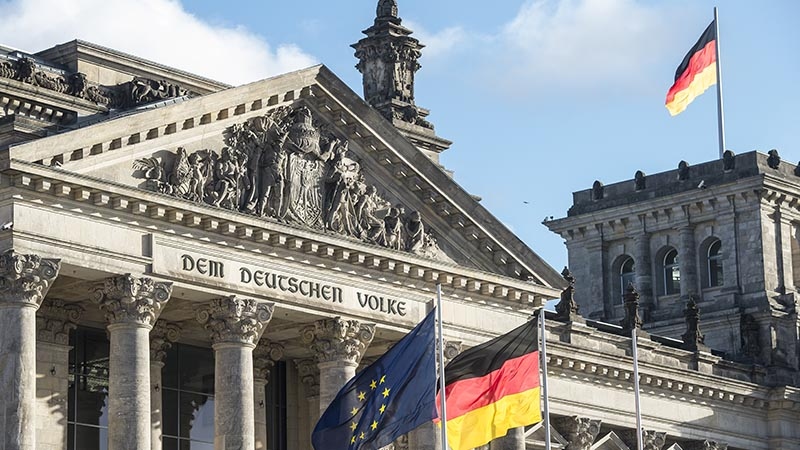 Detailansicht des Reichstagsgebäudes in Berlin mit der Inschrift „Dem deutschen Volke“ und Flaggen.