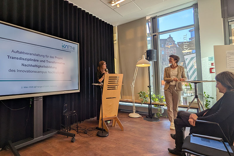 Frau h&auml;lt Rede an einem Stehpult, daneben ein Bildschirm mit Folie zur Auftaktveranstaltung f&uuml;r das Projekt TTNB.