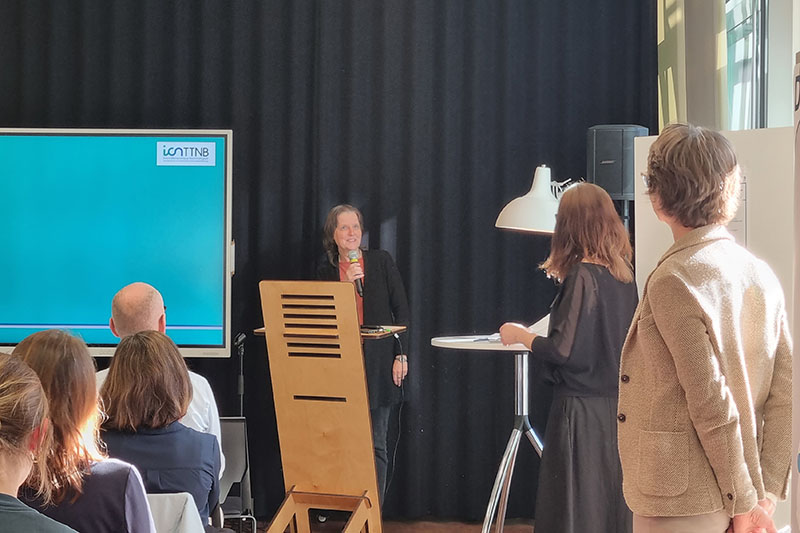 Kora Kristof h&auml;lt einen Vortrag am Stehpult vor Publikum.