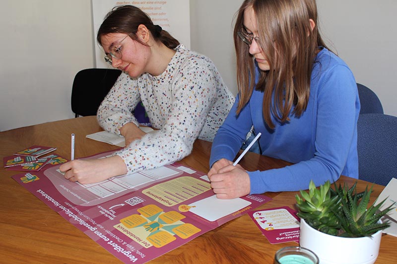 Zwei junge Personen arbeiten gemeinsam an einer Projektposter der climatechallenge.