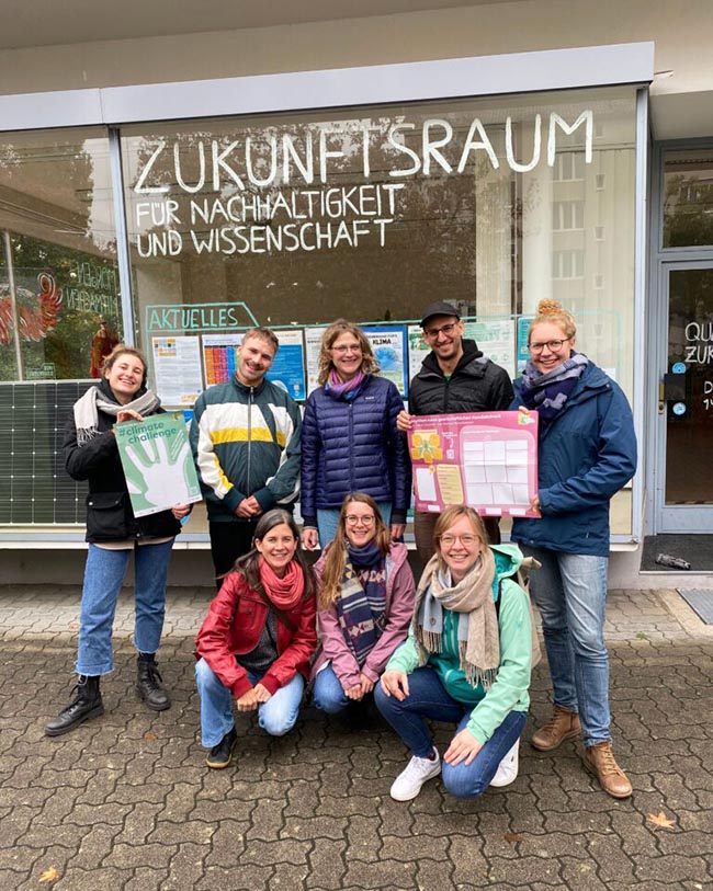 Gruppe von Menschen vor dem „Zukunftsraum für Nachhaltigkeit und Wissenschaft“, sie halten Plakate der climatechallenge in der Hand.