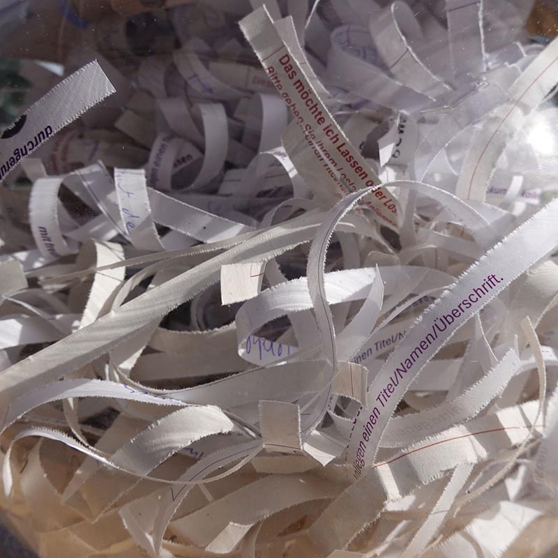 Nahaufnahme von geschreddertem Papier mit teilweise lesbaren deutschen Textfragmenten.