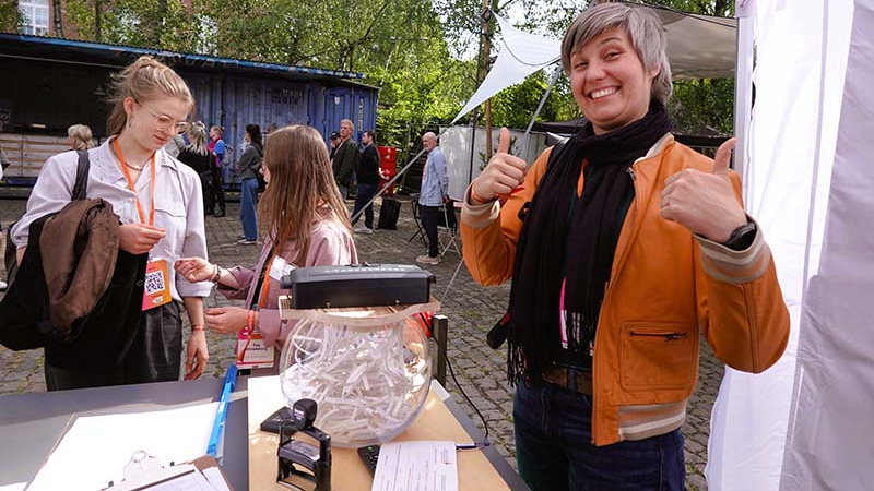 Fr&ouml;hliche Person mit Daumen-hoch-Geste an dem Amt f&uuml;r Lassen und Loslassen