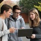 KIT-Studierende stehen vor einem Laptop