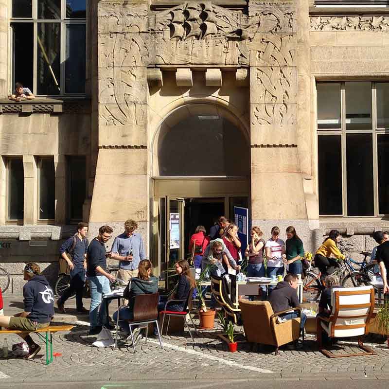 Menschen sitzen vor Gebäude