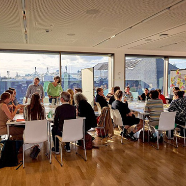 Mehrere Personen sitzen an Tischen und tauschen sich aus.