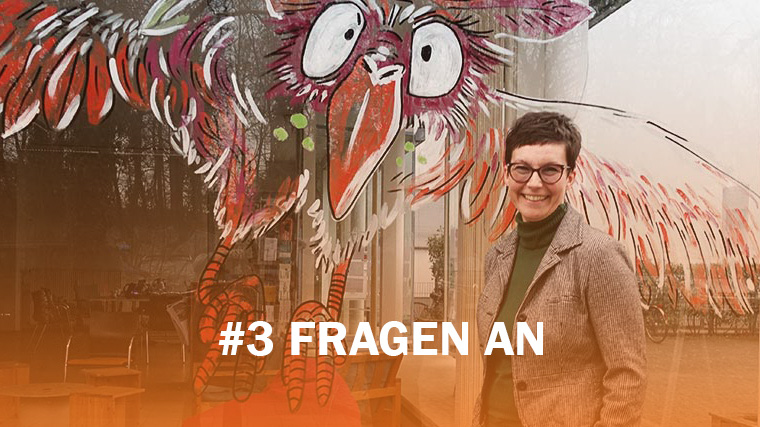 3 Fragen an Gabriella Kiss. Sie steht vor einem Fenster, auf dem ein Vogel gezeichnet ist.